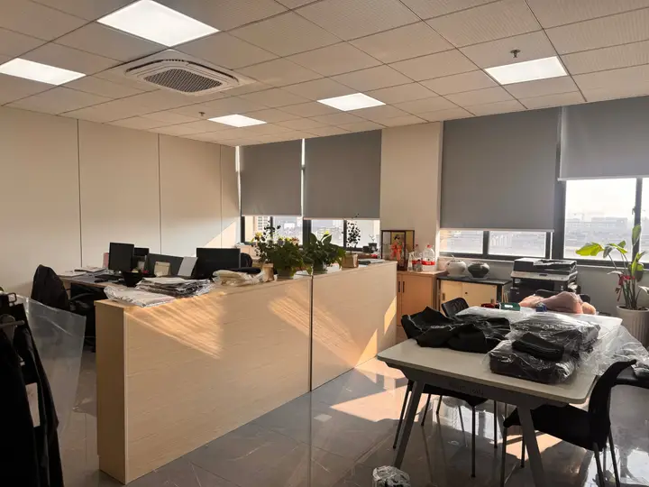 Office workspace with garment samples, computer desks, and plants